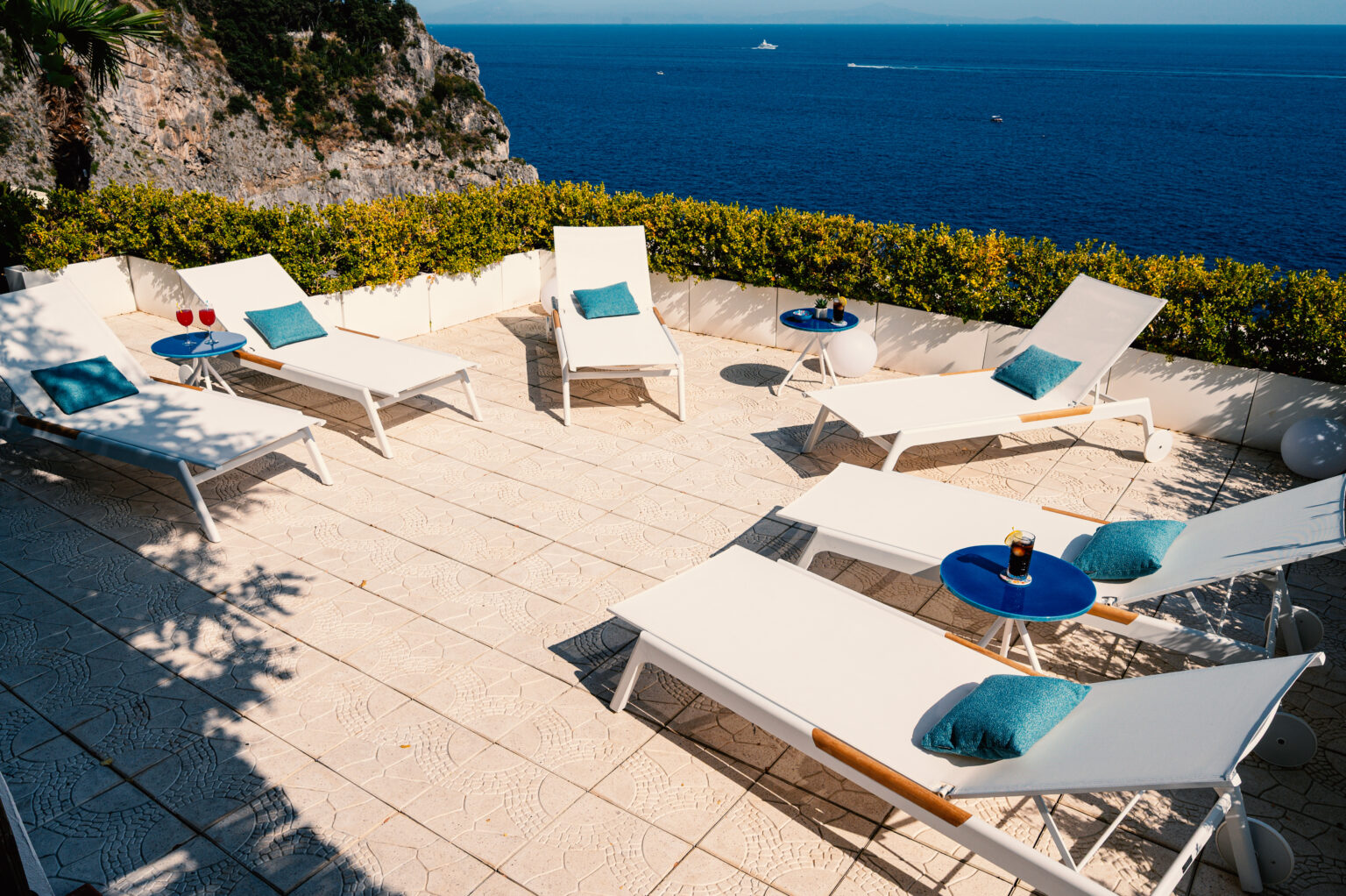 Luxury villa terrace in Italy featuring sun loungers and a stunning ocean view, perfect for relaxation and leisure. Ideal for vacation rentals in picturesque coastal settings. | Only on SopranoVillas