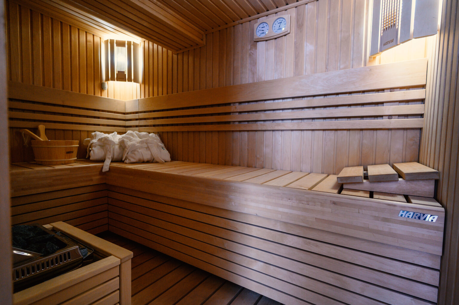 Interior of a wooden sauna featuring bench seating, a stone heater, and soft lighting, ideal for relaxation and wellness. | Only on SopranoVillas