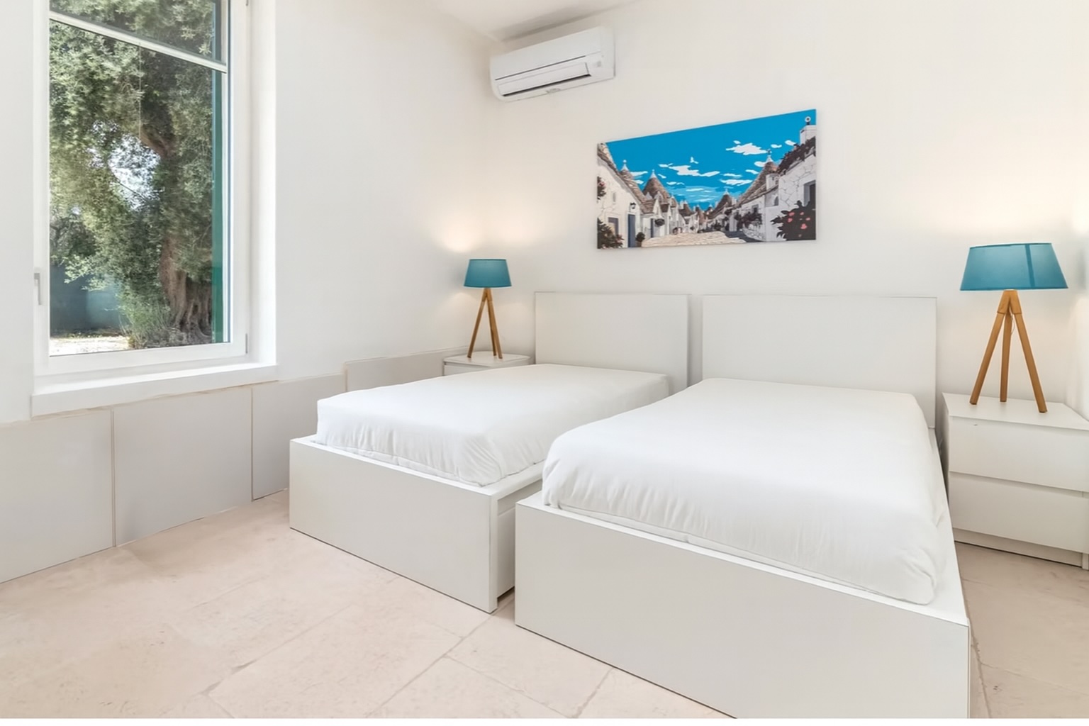 Luxury villa bedroom in Italy featuring two twin beds, modern decor, and stylish blue lamps, ideal for a relaxing getaway. | Only on SopranoVillas