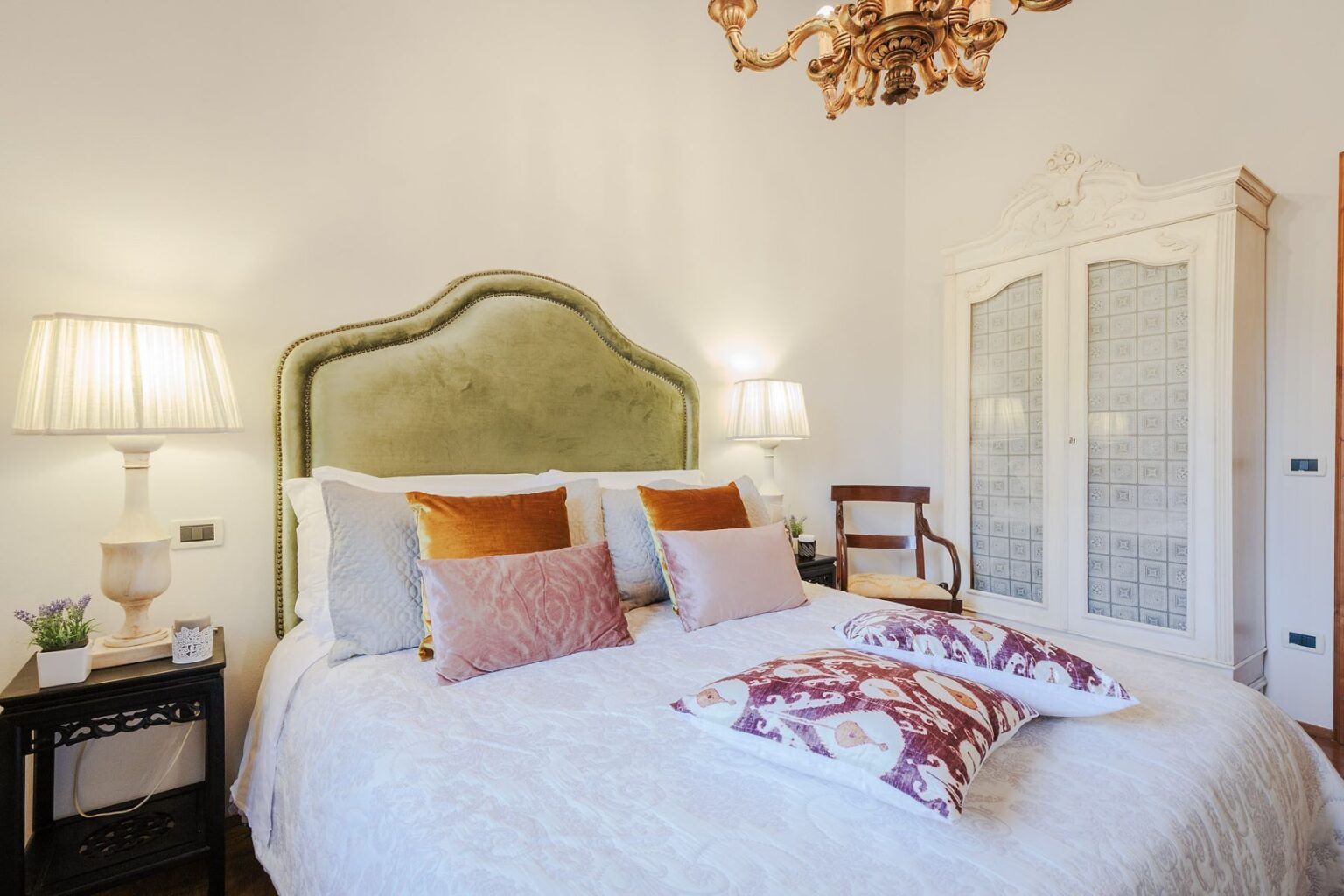 Cozy bedroom featuring a plush green headboard, decorative pillows, stylish bedside lamps, and an elegant wardrobe, creating a warm and inviting atmosphere. | Only on SopranoVillas