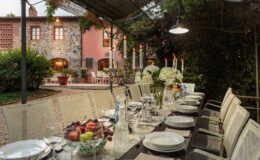 Elegant outdoor dining setup at a luxury villa in Italy, featuring a beautifully arranged table with fine china and a backdrop of lush gardens and classic architecture. Perfect for exclusive retreats and memorable gatherings.
