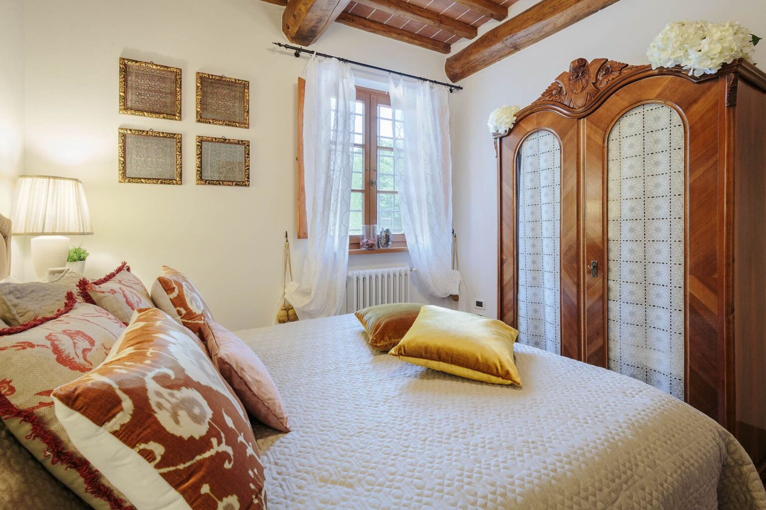 Cozy bedroom featuring a plush bed with decorative pillows, a wooden wardrobe, and soft lighting. The room has a rustic charm with exposed beams and elegant curtains, creating a warm and inviting atmosphere. | Only on SopranoVillas