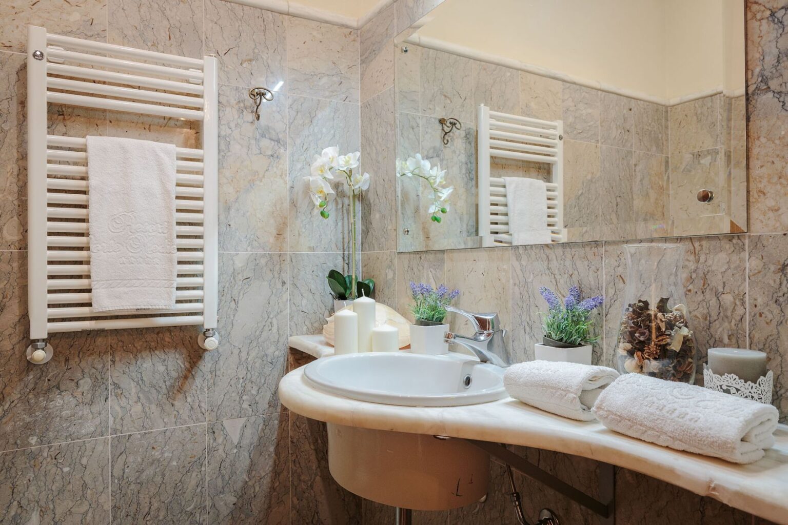 Luxury villa bathroom in Italy featuring elegant marble finishes, a stylish sink, fresh flowers, and plush towels, perfect for a relaxing getaway. | Only on SopranoVillas