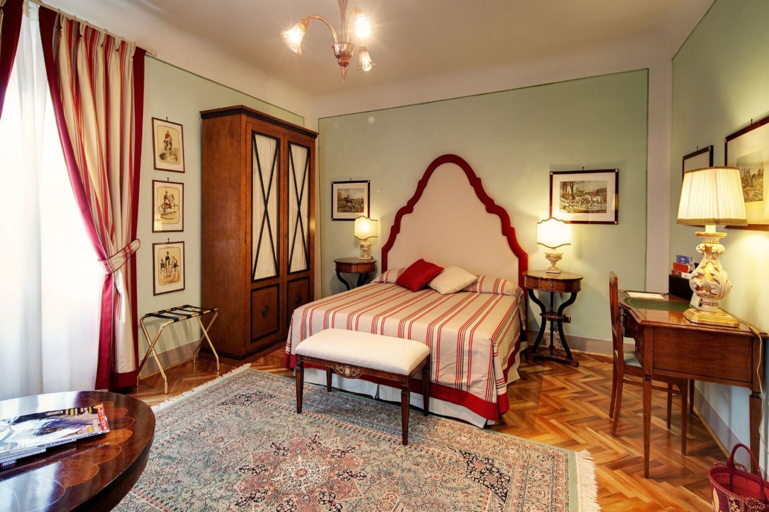 Cozy bedroom featuring a striped bedspread, elegant wooden furniture, and vintage decor. The room includes a bedside table with a lamp, a writing desk, and a large wardrobe. Natural light streams through the curtains, highlighting the patterned rug and warm color palette. Ideal for a relaxing stay. | Only on SopranoVillas