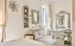 Elegant bathroom featuring a vintage clawfoot bathtub, ornate mirror, and stylish sink. Soft neutral tones and natural light enhance the serene atmosphere, complemented by decorative shelving and a cozy woven basket with towels. Ideal for relaxation and aesthetic inspiration.
