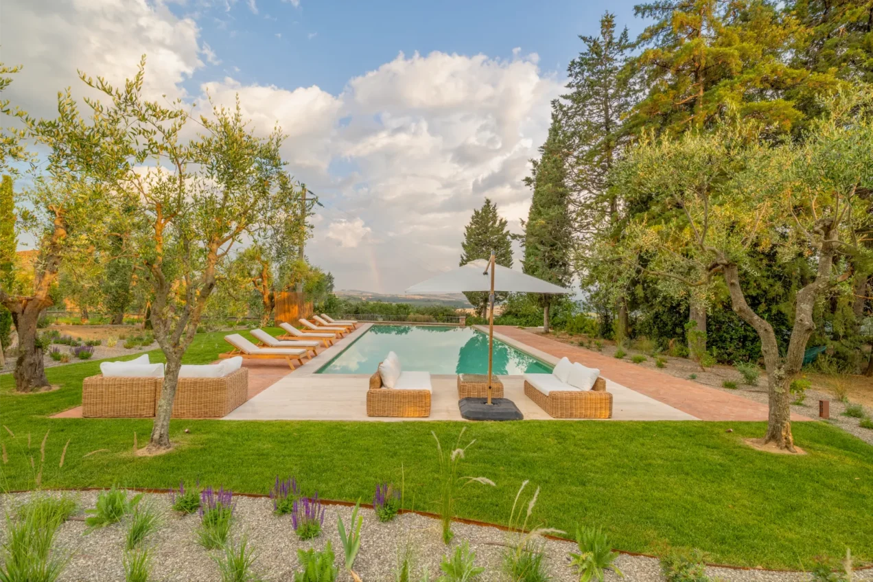 Luxurious outdoor pool area surrounded by olive trees and lush greenery, featuring comfortable seating and sun loungers, ideal for relaxation and leisure in a scenic landscape. | Only on SopranoVillas