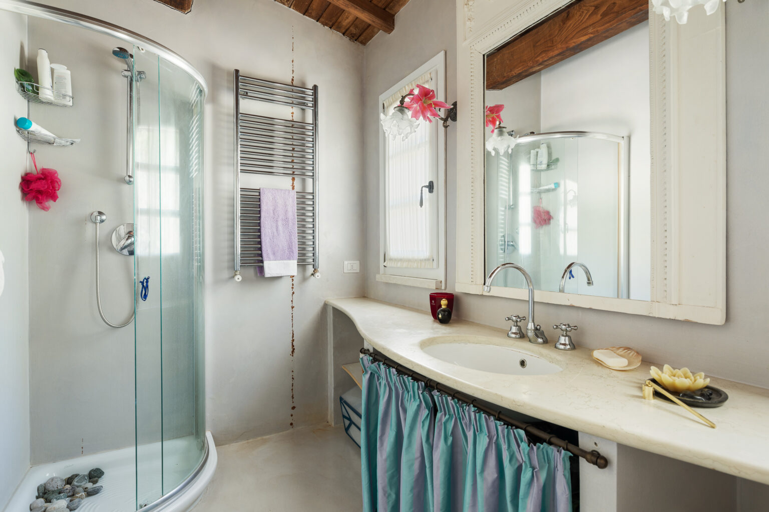 Modern bathroom interior featuring a glass shower enclosure, stone accents, a sleek vanity with a marble countertop, and decorative elements like a towel rack and flower accents. The design combines functionality with a stylish aesthetic, ideal for a relaxing space. | Only on SopranoVillas