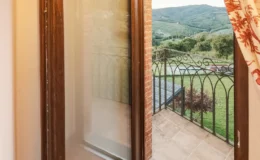 Elegant arched windows framing a picturesque view of rolling hills and green landscapes, with a balcony overlooking a serene outdoor space.