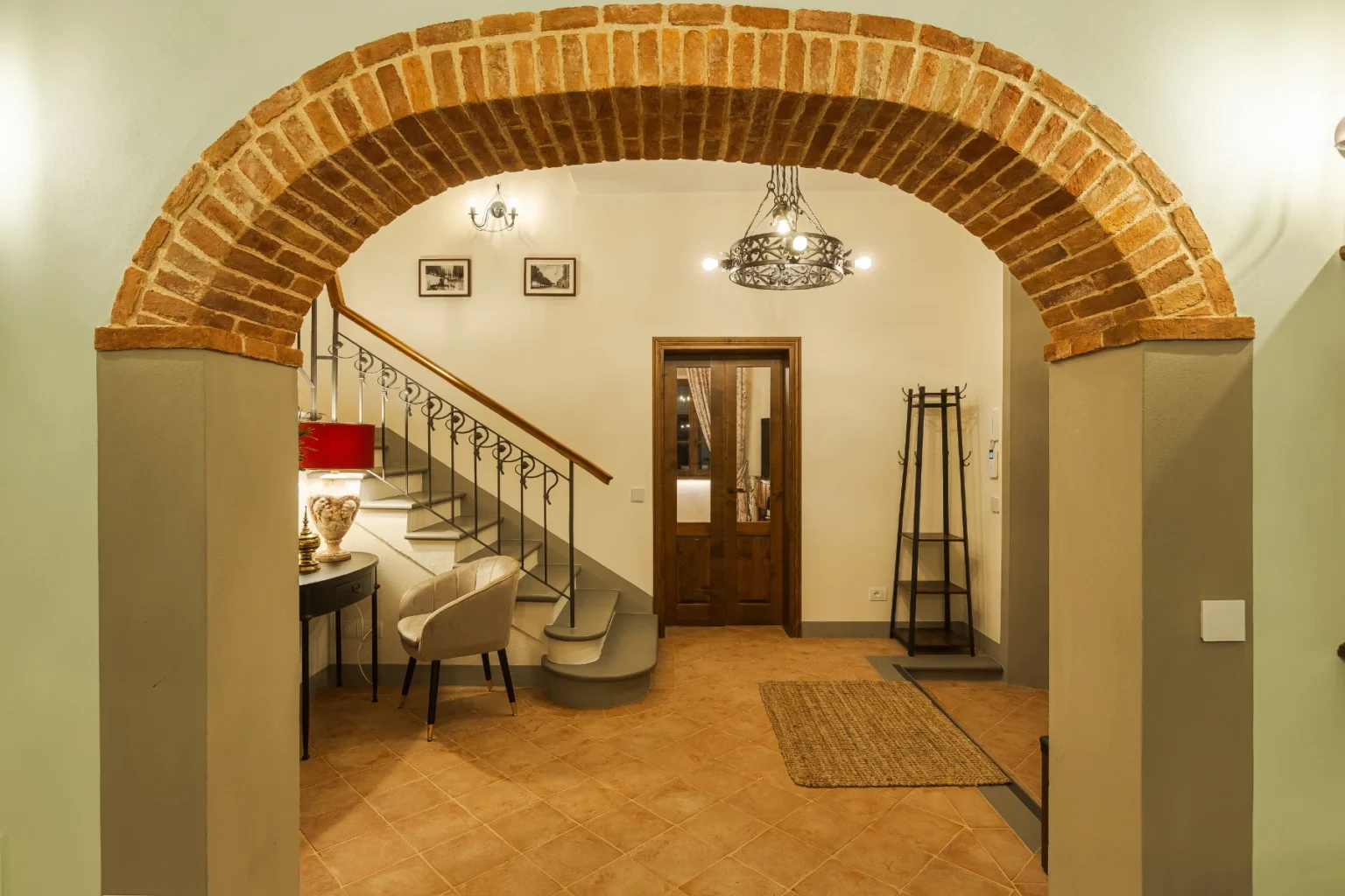 Welcoming interior entrance featuring a brick archway, a stylish staircase, and elegant decor, including a chair and lamp, creating a cozy atmosphere. | Only on SopranoVillas