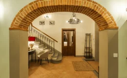 Welcoming interior entrance featuring a brick archway, a stylish staircase, and elegant decor, including a chair and lamp, creating a cozy atmosphere.