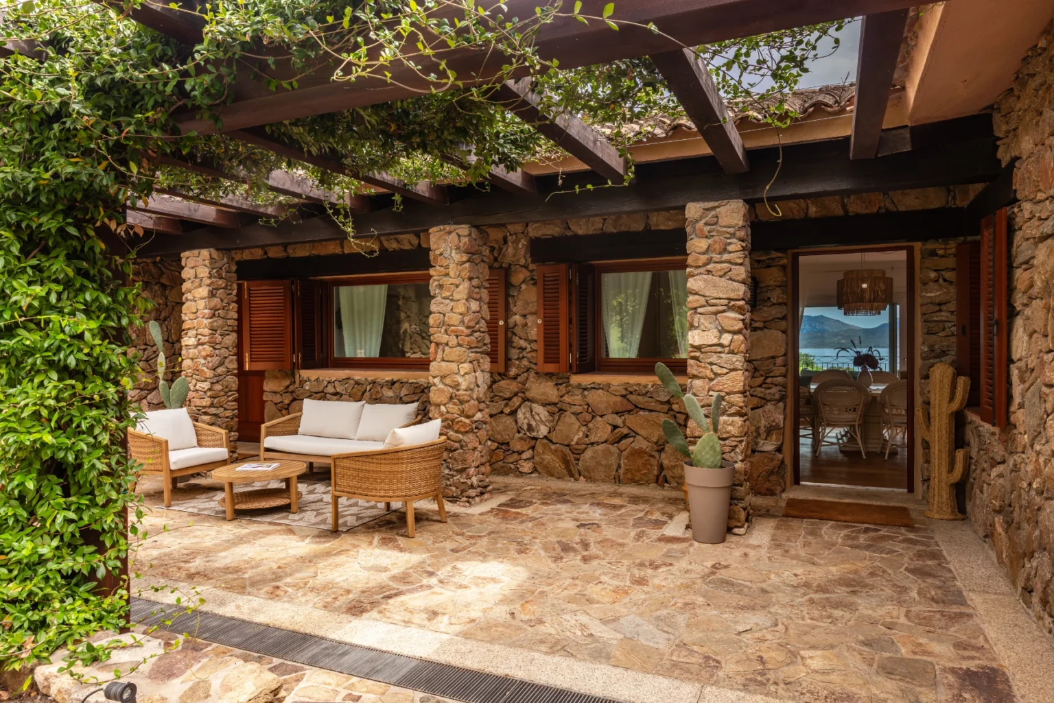 Cozy outdoor seating area with stone walls, wooden beams, and lush greenery, perfect for relaxation and enjoying scenic views. | Only on SopranoVillas