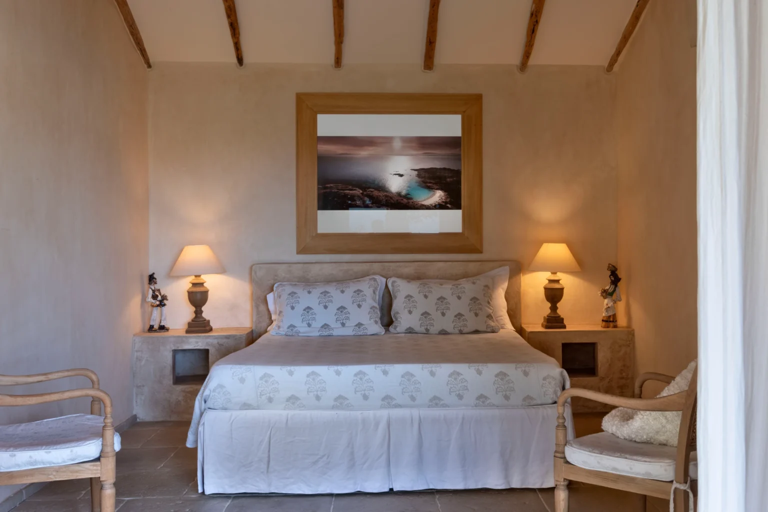 Luxurious bedroom in a villa for rent in Italy, featuring a king-sized bed with elegant linens, soft lighting, and tasteful decor, creating a serene and inviting atmosphere. | Only on SopranoVillas