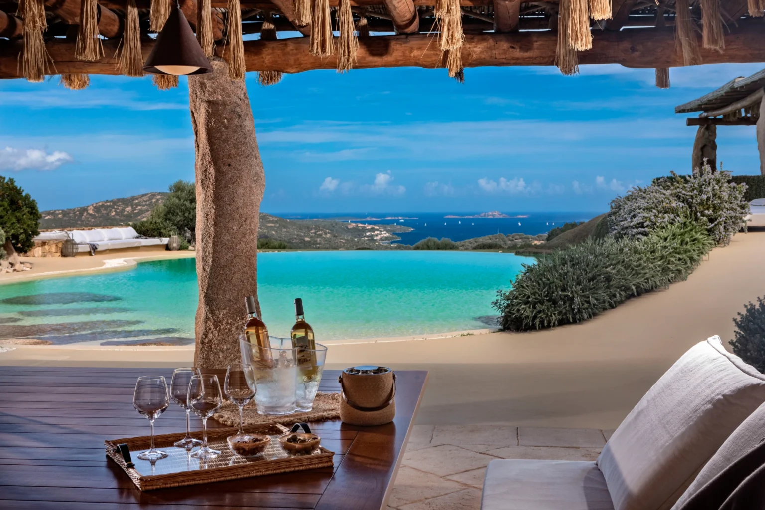 Luxury villa rental in Italy featuring a stunning infinity pool with a panoramic view of the coastline, elegantly designed outdoor dining area, and tropical landscaping, perfect for a serene getaway. | Only on SopranoVillas