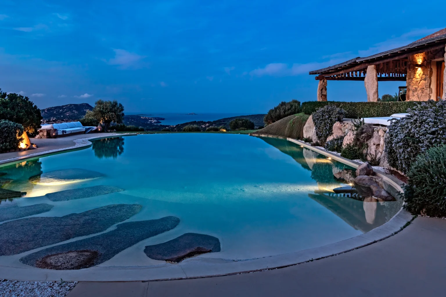 Luxury villa with a stunning infinity pool at twilight, surrounded by lush gardens and offering breathtaking views of the Italian countryside, perfect for vacation rentals. | Only on SopranoVillas