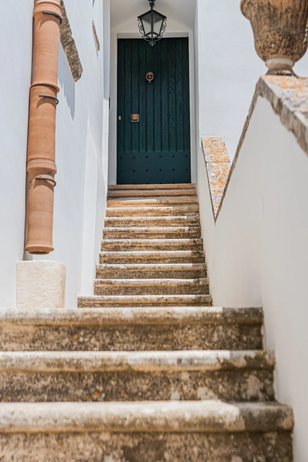 Stone staircase leading to a green door, framed by white walls and terracotta accents. | Only on SopranoVillas