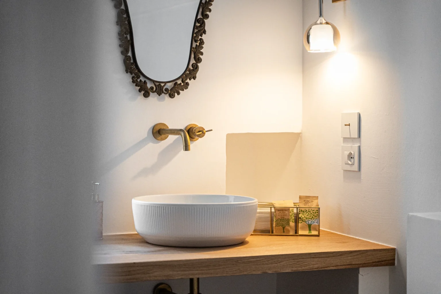 Modern bathroom interior featuring a stylish round sink on a wooden countertop, a decorative mirror, and warm lighting, creating a cozy ambiance. | Only on SopranoVillas