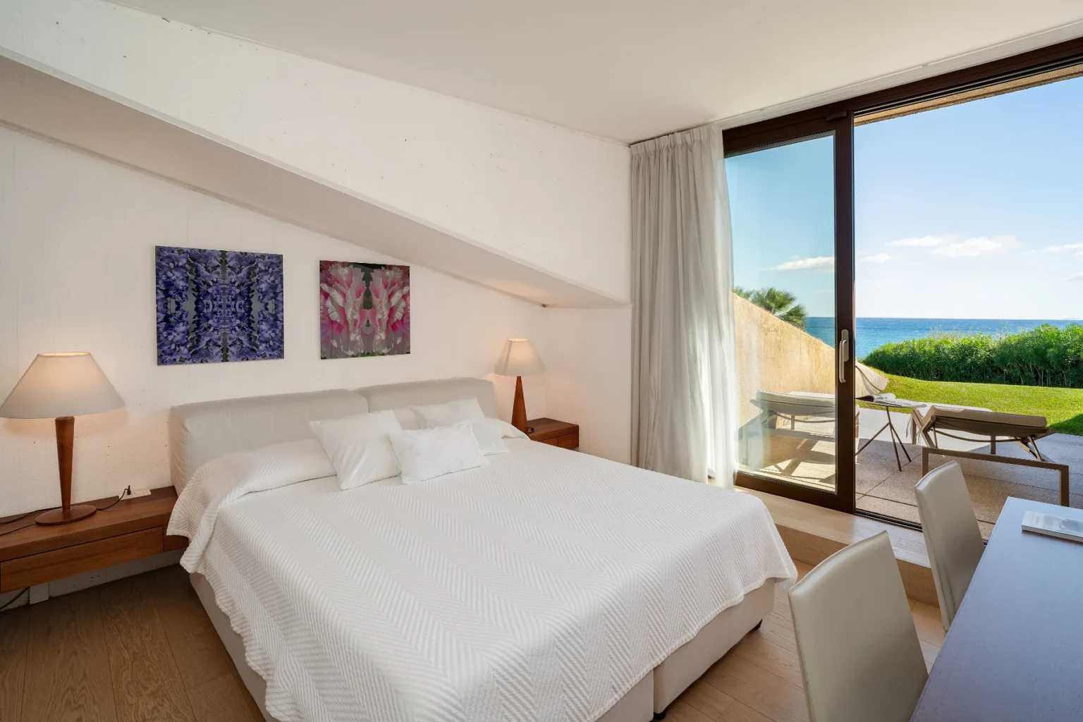 Modern hotel room with a king-sized bed, featuring coastal views through large windows, stylish decor, and a private balcony. Ideal for a relaxing getaway. | Only on SopranoVillas
