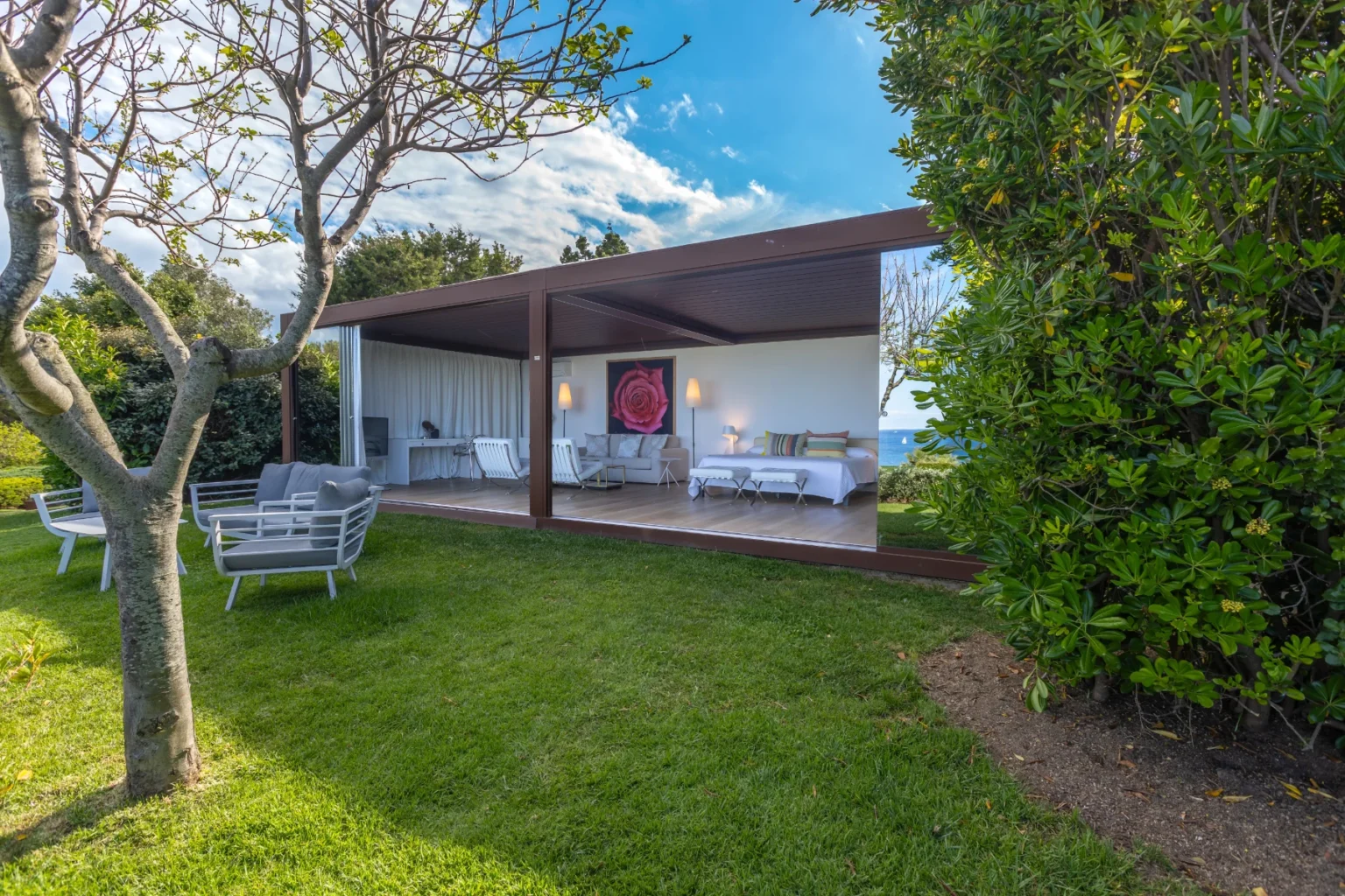 Modern outdoor living space featuring a stylish covered patio with comfortable seating, surrounded by lush greenery and a scenic view. Ideal for relaxation and entertaining in a tranquil garden setting. | Only on SopranoVillas