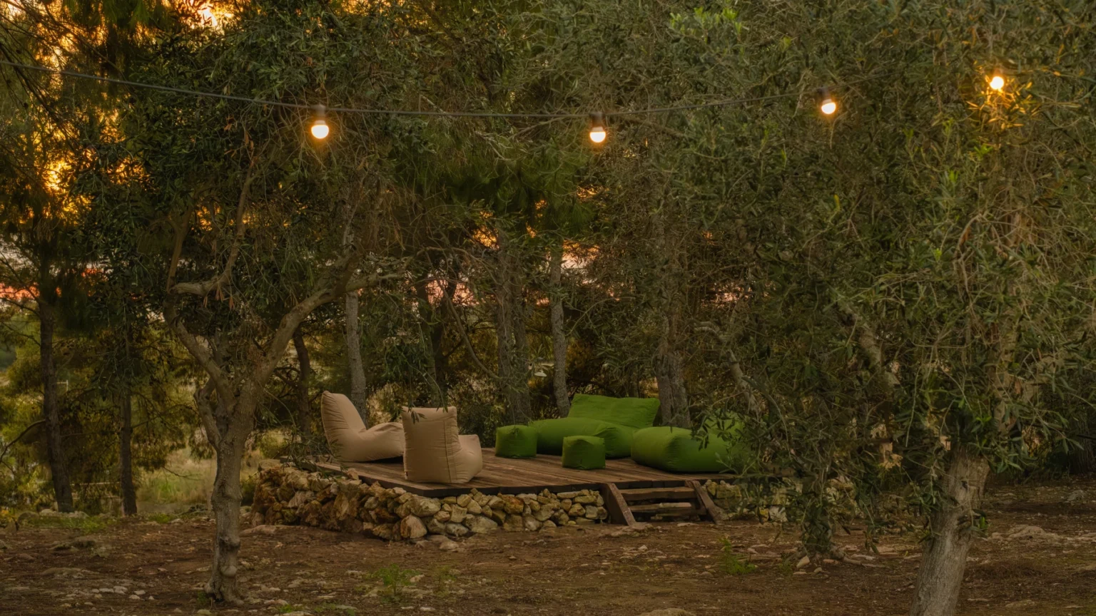 Cozy outdoor seating area surrounded by trees, featuring decorative string lights and manicured greenery, perfect for relaxation and gatherings. | Only on SopranoVillas