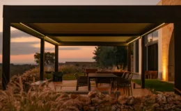 Modern outdoor patio with a sleek pergola, featuring a dining table and chairs, surrounded by lush greenery and a sunset view. Ideal for outdoor entertaining and relaxation.