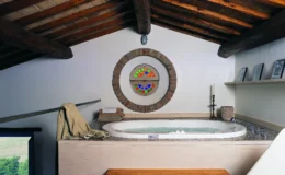 Modern spa bathroom with a circular hot tub, wooden beams, and decorative wall art, creating a relaxing atmosphere.