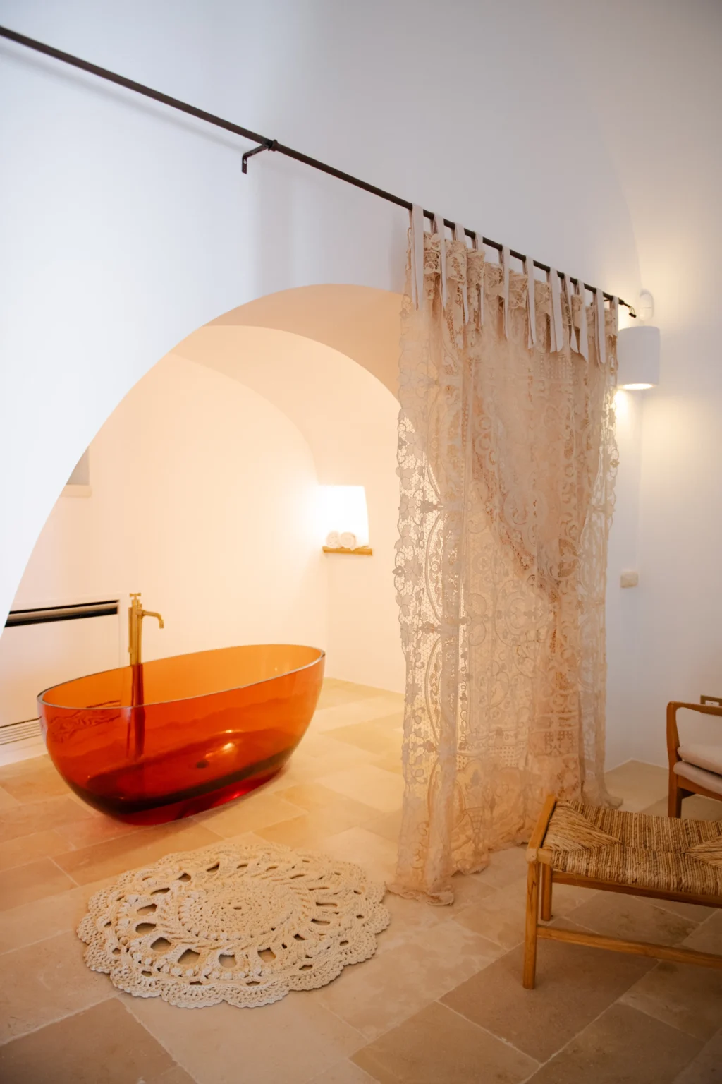 Modern bathroom interior featuring an elegant orange freestanding bathtub, soft lighting, and decorative sheer curtains, creating a serene and stylish atmosphere. | Only on SopranoVillas