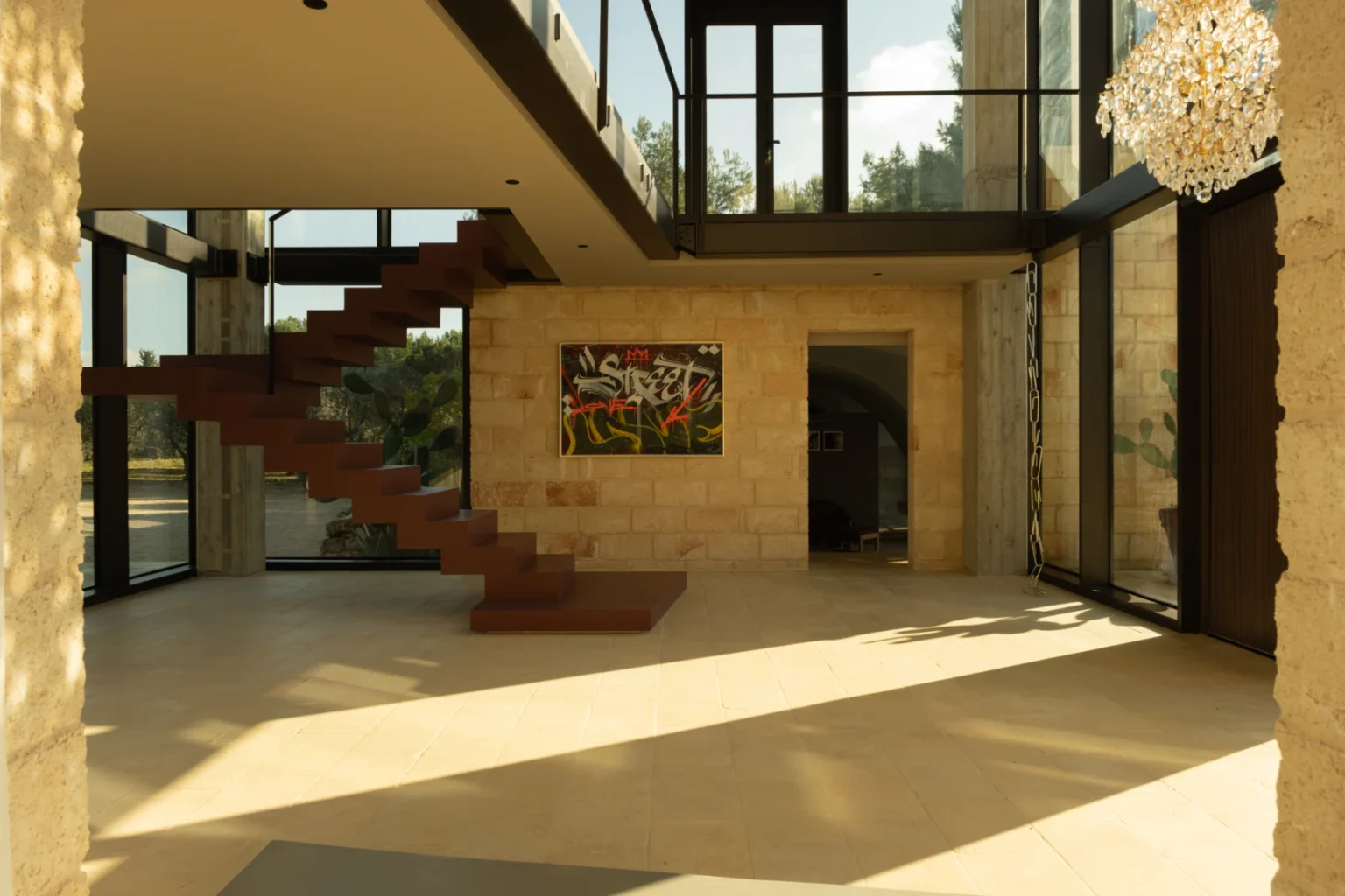 Modern interior of a spacious foyer featuring large glass walls, a wooden staircase, and contemporary artwork, illuminated by natural light. | Only on SopranoVillas