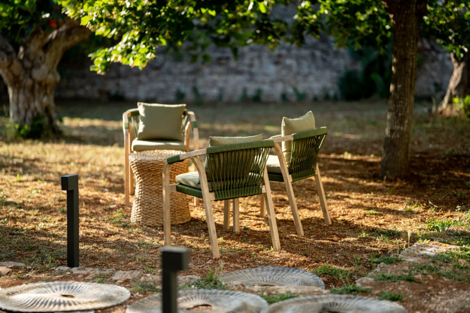 Cozy outdoor seating area with green chairs and a small table surrounded by trees and natural landscaping. Perfect for relaxation and gatherings in a garden setting. | Only on SopranoVillas