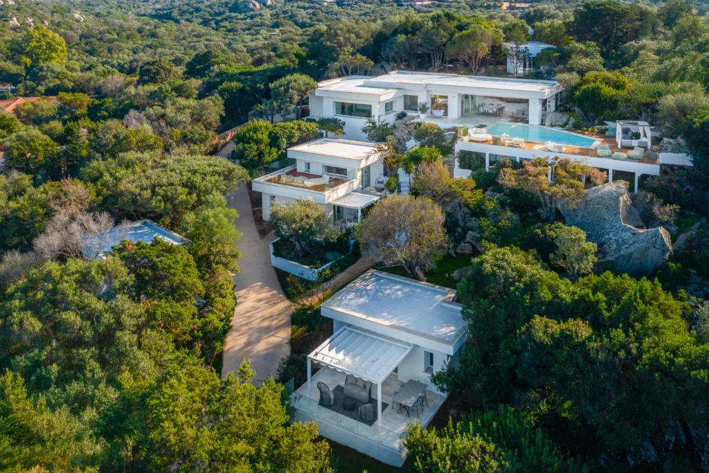 Aerial view of a modern luxury villa surrounded by lush greenery, featuring multiple buildings, a swimming pool, and a winding driveway. Ideal for showcasing upscale real estate in a natural setting. | Only on SopranoVillas