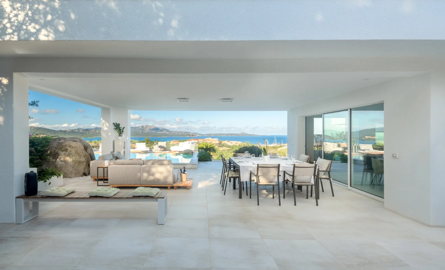 Modern outdoor living space featuring a dining area and lounge with scenic views, surrounded by natural landscape. Ideal for entertaining and relaxation. | Only on SopranoVillas