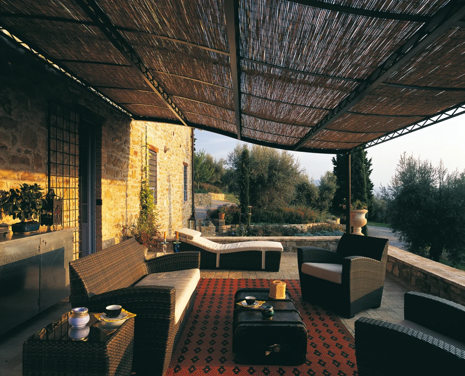 Cozy outdoor patio with wicker furniture and a shaded area, surrounded by greenery and stone walls, ideal for relaxation and entertaining. | Only on SopranoVillas