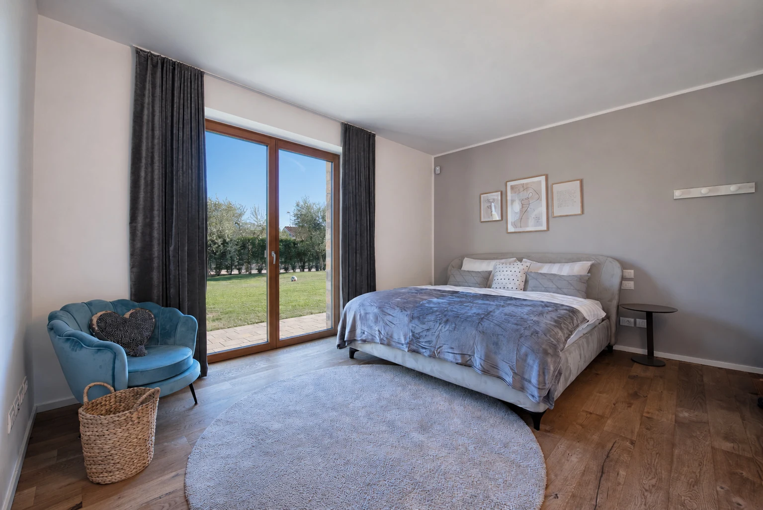 Bedroom with grey bedding, a blue armchair and glass doors facing the garden. | Only on SopranoVillas