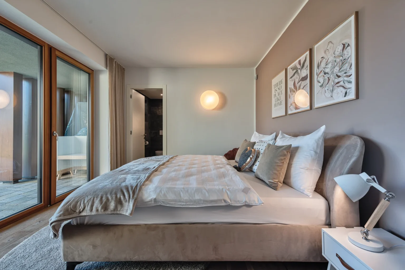 Bedroom with an upholstered bed, patterned cushions and full-height glass doors. | Only on SopranoVillas