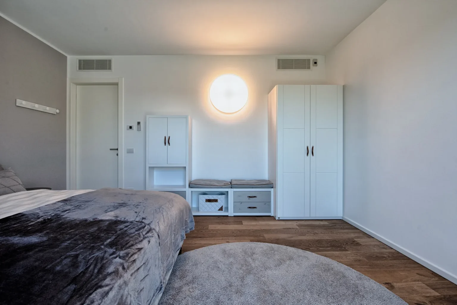 Bedroom viewed from the bed towards white wardrobes, a bench and a round wall light. | Only on SopranoVillas