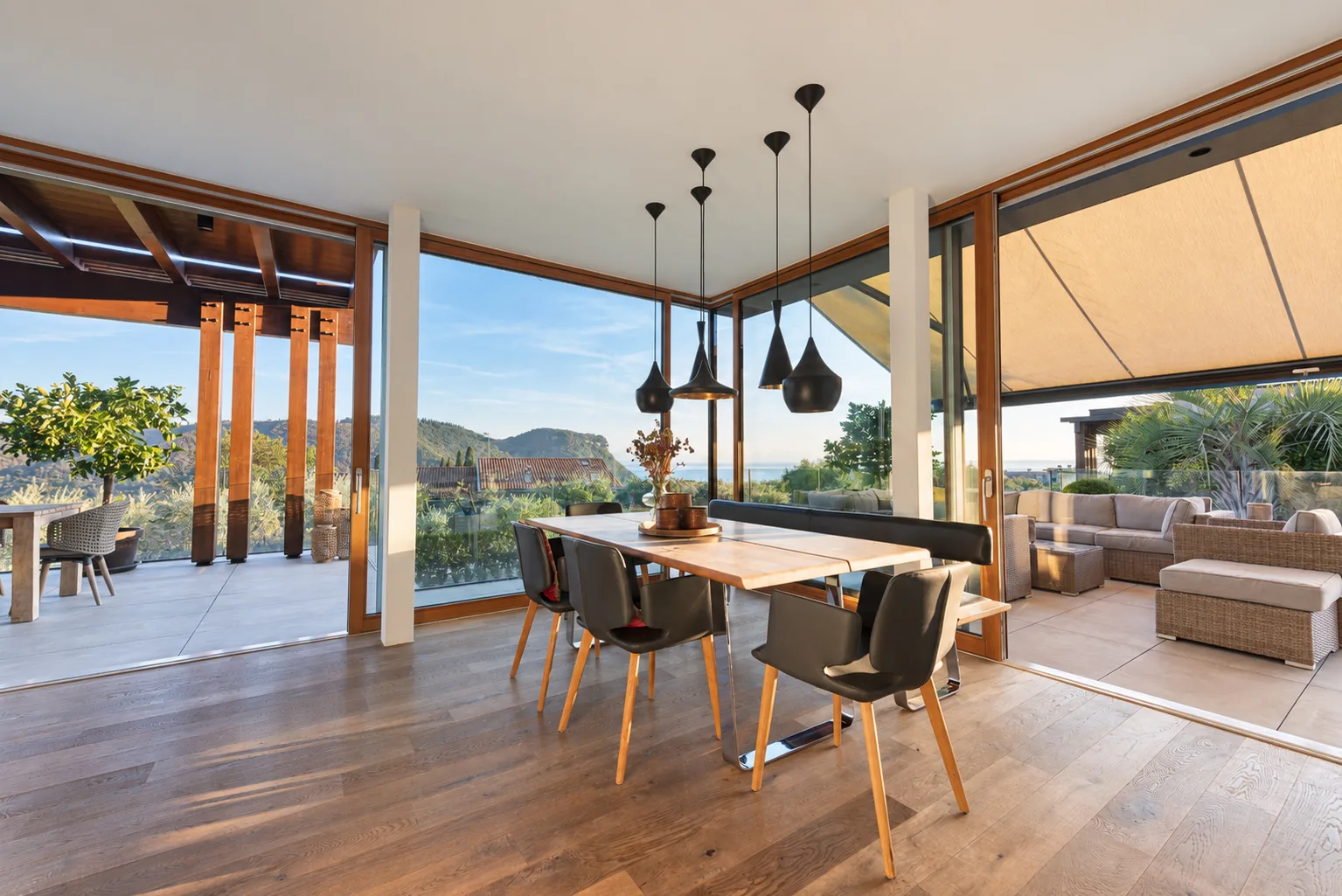 Dining table beside full-height glass doors opening onto a furnished terrace. | Only on SopranoVillas