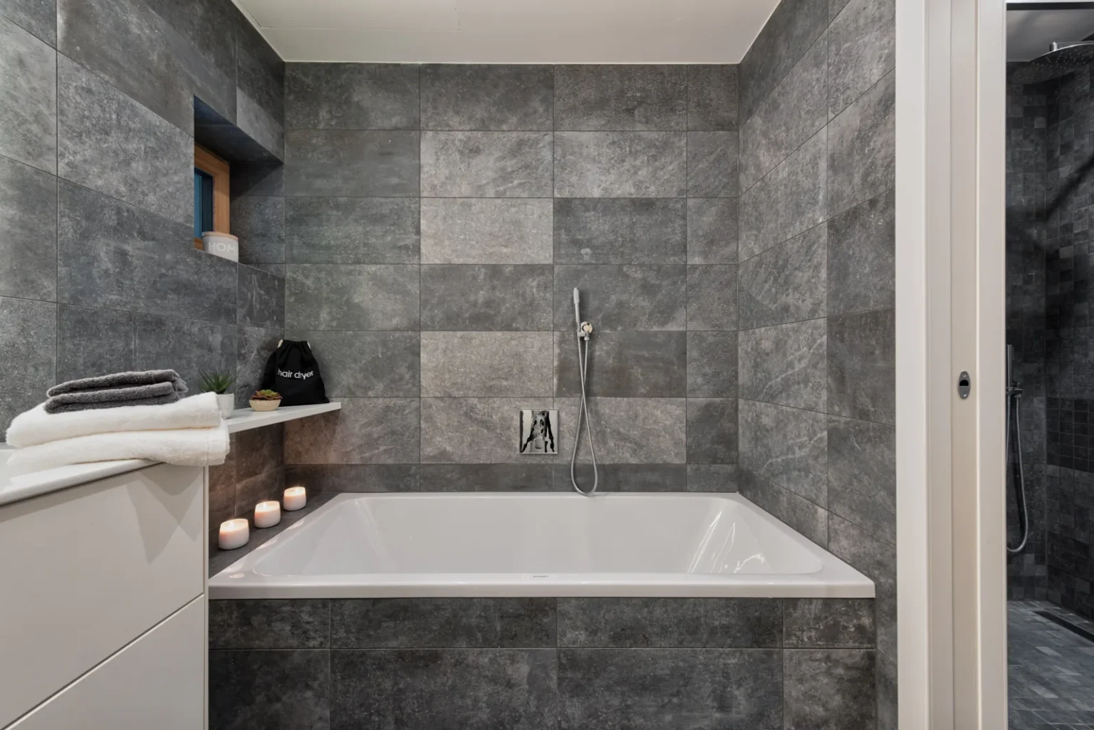 Built-in bathtub against grey tiled walls, with a glazed shower enclosure beside it. | Only on SopranoVillas
