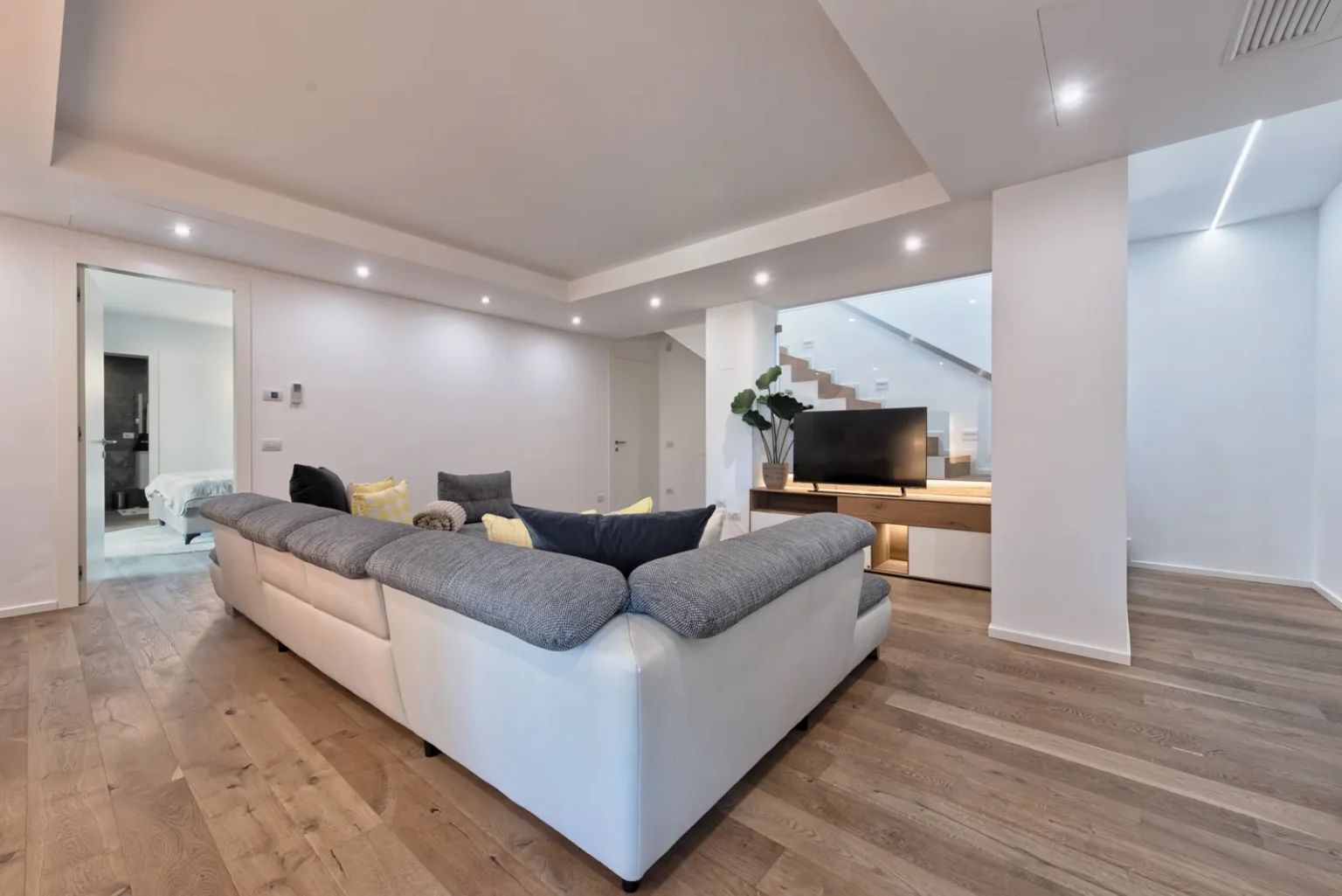 Reverse view of the living room, showing the sectional sofa, television and open circulation space. | Only on SopranoVillas