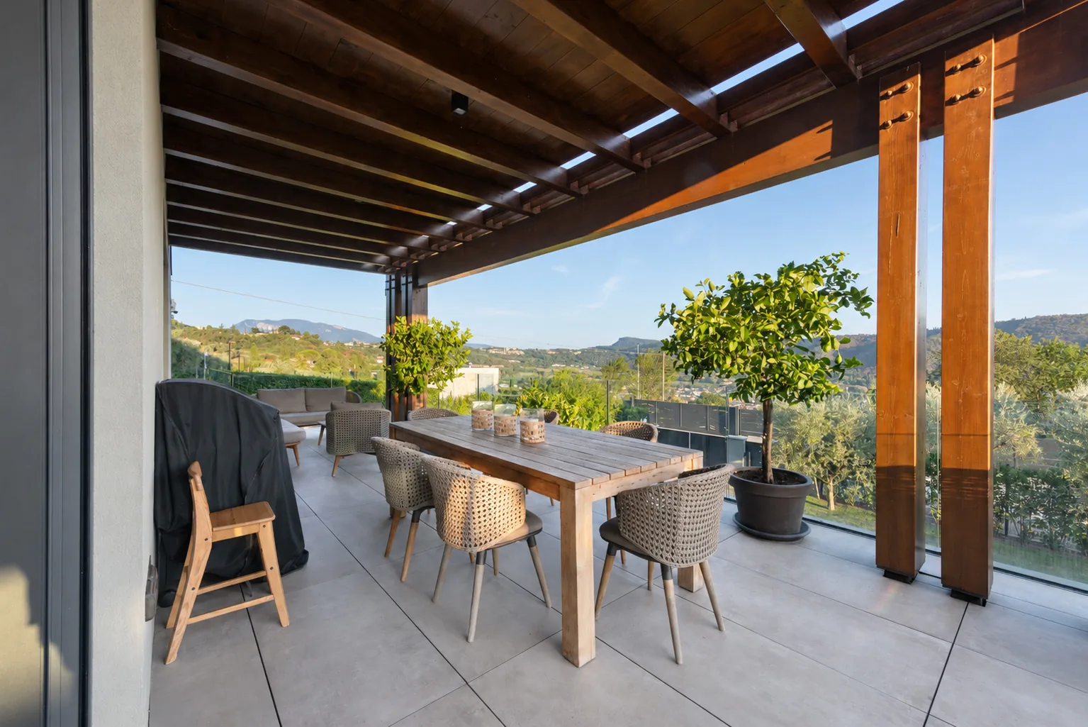 Outdoor dining table beneath a timber pergola, beside glass railings and potted plants. | Only on SopranoVillas